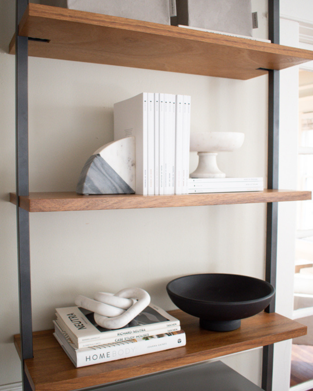 Home decor - image features a marble bowl, book end, and black wooden bowl sitting on wooden shelves. The image represents the selection of decorative objects we sell for your home. Sterling Harper specializes in Scandinavian, minimal home decor.